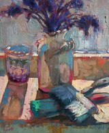 Still life painting with purple flowers in a white vase, brushes and a glass, illuminated by the sunlight